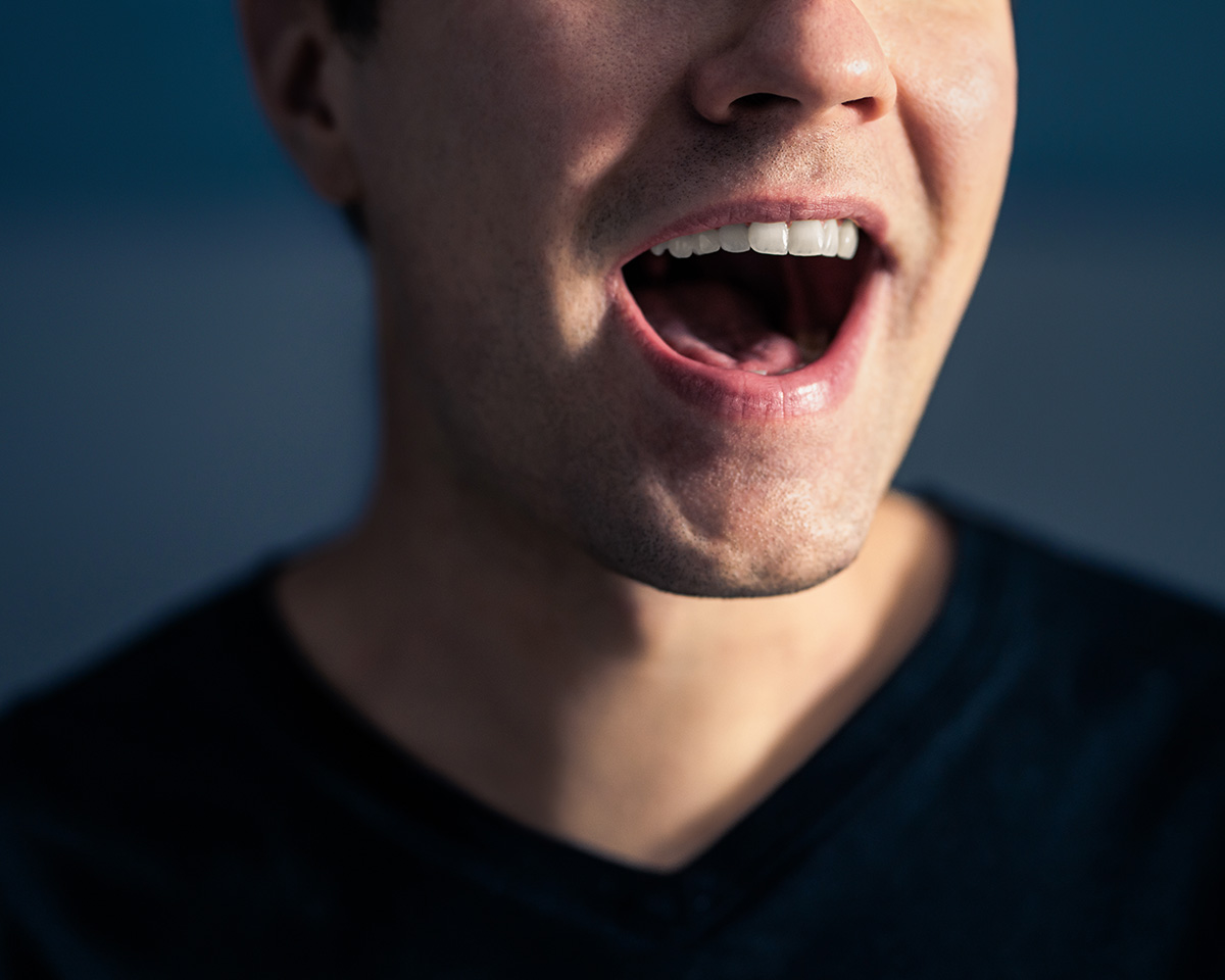 Mann mit offenem Mund, der spricht, sichtbar von der Kinnlinie bis zu den Lippen.